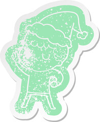 quirky cartoon distressed sticker of a grumpy boy wearing santa hat