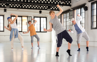 One young lady and few boys dancing modern dance on rehearsal