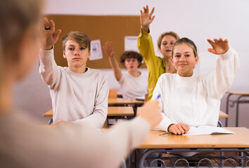 Students raise their hand to answer during a lesson in class