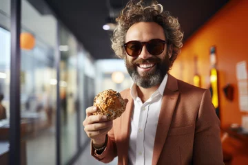 Fotobehang Picture of man wearing suit and sunglasses, holding sandwich. This image can be used to depict professional enjoying quick meal on go © vefimov