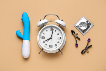 Alarm clock with sex toys on beige background