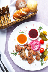 chicken kebab on a white plate with sauce and vegetables