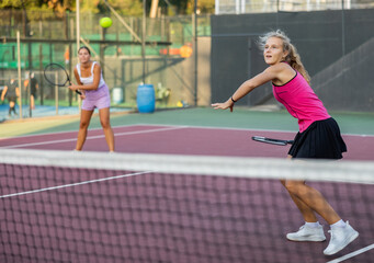 Obraz premium Caucasian young woman in tank top and skirt playing tennis match during training on court.