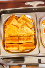 Pancakes in a stainless steel tray on a wooden table.
