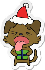 hand drawn sticker cartoon of a dog with christmas present wearing santa hat