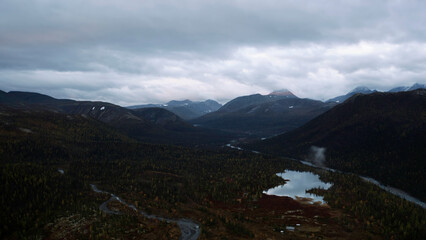 Aerial view of the natural reserve on an autumn day. Clip. Mountain range and heavy cloudy sky above forested valley.