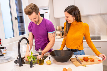 Couple washing the ingredients for a salad at home