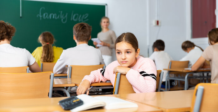 Portrait of upset tired teenage schoolgirl sitting in classroom secondary school - Powered by Adobe