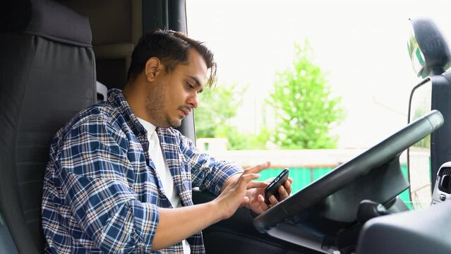 Indian trucker sits in his truck and using truck gps navigation