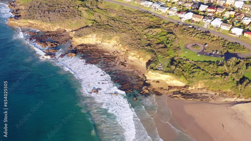 Sticker Pacific ocean scenic aerial flying over coastal edge with caves and beach 4k.
