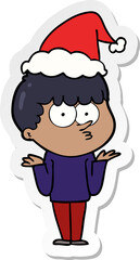 hand drawn sticker cartoon of a curious boy shrugging shoulders wearing santa hat