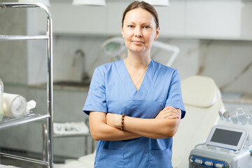 Adult female cosmetologist in medical uniform posing in medical room