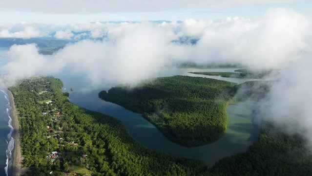 Aerial shot of a river winding through the clouds in Costa Rica, with a mix of sunshine and clouds. Beautiful contrast between the water and the jungle. Zancudo
