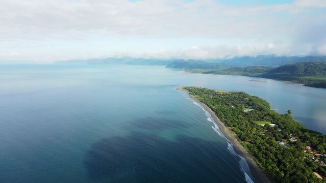 Aerial shot of the Costa Rican coastline with blue sky and scattered clouds. Zancudo village in Puntarenas province near Golfo Dulce is visible.