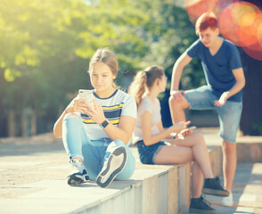 Teenagers are playing on smartphone on city street