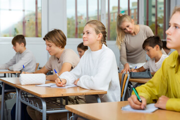 Fototapeta premium Young boys and girls studying in classroom during lesson in school.