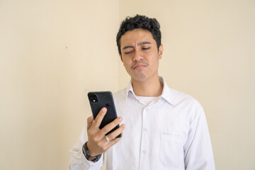 Indonesian office employee wear white clothes feel stress and unhappy expression when calling on phone. The photo is suitable to use for man expression advertising and fashion life style.