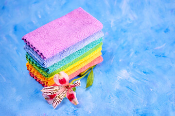 a variegated alstroemeria flower and seven rainbow colored cleaning rags lie on top of each other...