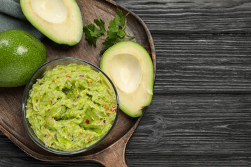 Delicious guacamole with parsley and fresh avocado on wooden table, flat lay. Space for text