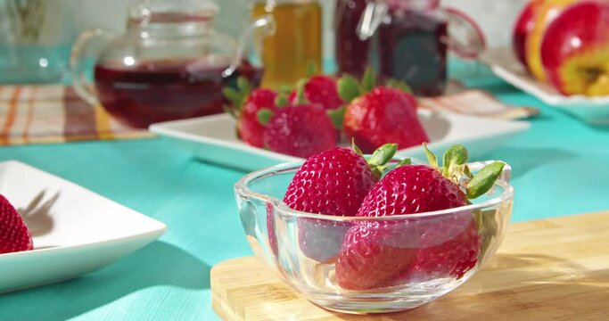 Chocolate covered strawberries in a transparent bowl on the table with sweets.