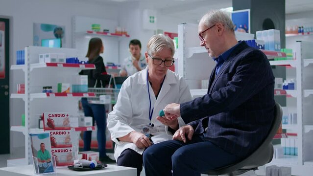 Elderly pharmacist in drugstore using medical device to check senior patient glucose levels in blood. Knowledgeable druggist using medicinal diabetic tool on client in annual checkup