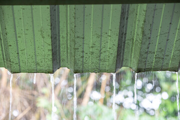 Rain drops on the roof of a house with a green background.