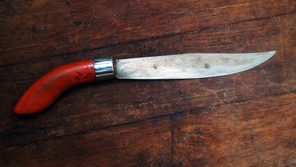 Indonesian antique knife. Brown wooden handle. On a wooden table