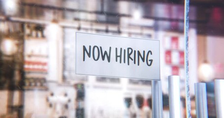 Storefront with Now Hiring sign on the window pane