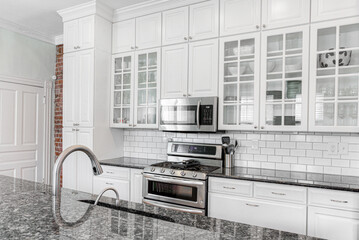 Modern White Kitchen Interior with Exposed Brick Wall and Subway Tile and Glass Cabinets