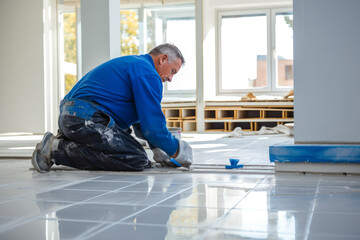 Tile installer, a man laying floor tiles in a new home, demonstrating the expertise and precision of a professional contractor