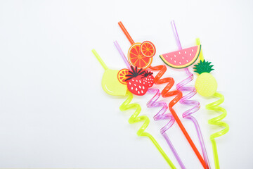 close up colorful fruit drinking staws on white background