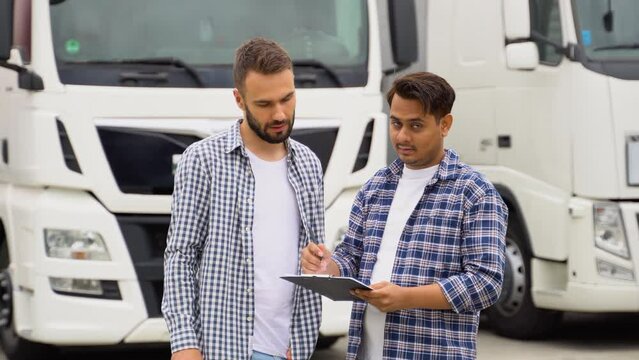 Indian manager and trucker standing by truck with a clipboard, checking the delivery list