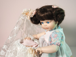 Vintage biscuit-porcelain doll girl plays with a baby doll in a cradle decorated with lace.  - 654103155