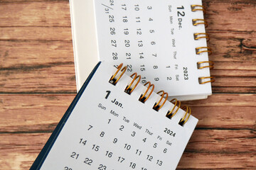 January 2024 and December 2023- Closeup of a small desktop calendar with wooden table background,...