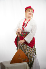Cheerful funny adult mature woman solokha with musical balalaika. Female model in clothes of...