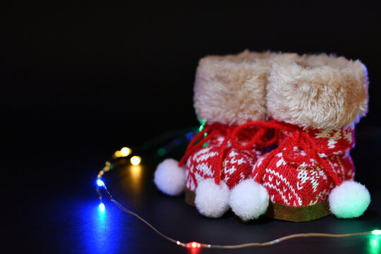 Botas de color rojo y luces de colores sobre fondo negro, concepto navide&ntilde;o. Espacio para texto al lado izquierdo.