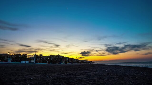 Sunrise from the beach of Torrox in Spain with the town and palm trees in the background