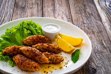 Kibbeh - Arabic style seared meatballs mixed with bulgur groats and mint yogurt on wooden table
