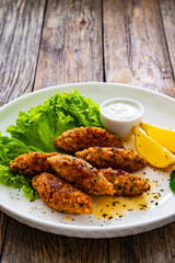 Kibbeh - Arabic style seared meatballs mixed with bulgur groats and mint yogurt on wooden table
