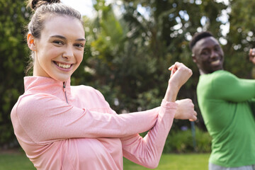 Portrait of happy diverse couple practicing yoga and stretching in garden