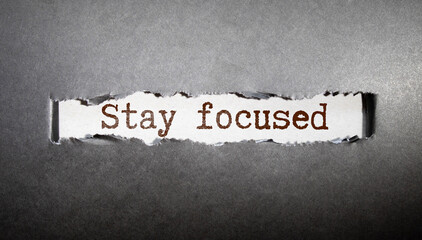 says Stay focused written on sticky note pinned on wooden wall