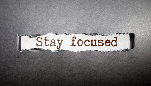 says Stay focused written on sticky note pinned on wooden wall