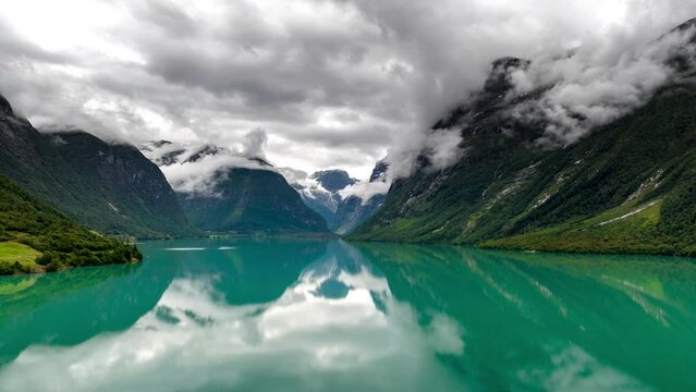 Drone hyperlapse over Loen Lake of mountain fog twirling around Loen mountains