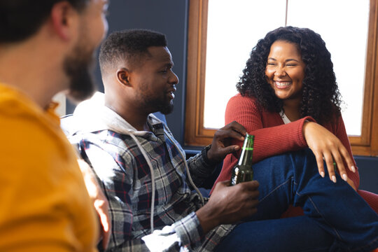 Happy Diverse Male And Female Friends Talking And Drinking Beer At Home