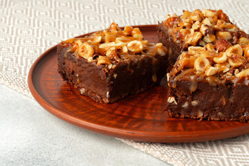 Fototapeta na wymiar Brownie cake with nuts topping on plate close up