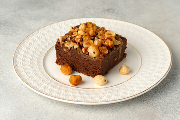 Brownie cake with nuts topping on plate close up