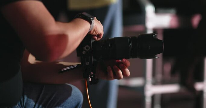 Backstage professional fashion photo shoot. Unknown professional photographer at work in the studio. No flash light. A male photographer at work in a professional photo studio. No face visible