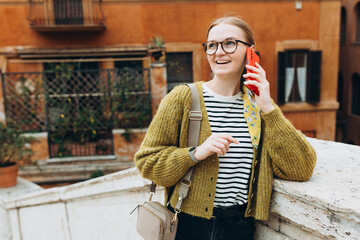 Fototapeta Happy young blonde woman talk phone, listen at the street. Phone Communication. Feminine gossip while relaxing on urban background, traveler obraz