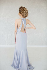 Fototapeta na wymiar Full-length girl in lilac long dress with open back and evening hairstyle