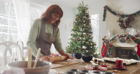 Slow Motion Portrait of Senior Female Making Gingerbread Cookies for Christmas at Home. Grandmother Happily Making Pastries to Share with Family and Friends, Preparing for Holiday Gathering and Dinner - Powered by Adobe